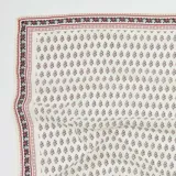 Pañuelo cuadrado de tela fina color crema con estampado de flores pequeñas en rojo y negro.
