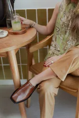 Mules de cuero negro con punta cuadrada y detalle de tachas plateadas en el borde superior.