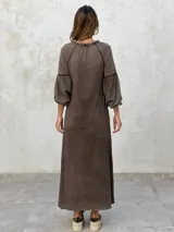 Vestido largo color marrón, de corte suelto, con mangas largas abullonadas y escote en V.