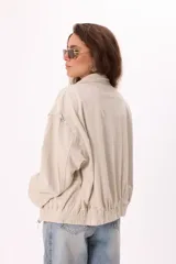 Campera color crema tipo gamuza con cierre frontal, cuello clásico, mangas largas y calados florales en hombros y espalda.