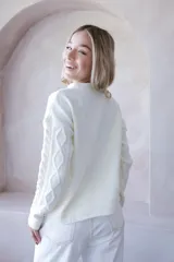 Sweater color crema de punto con diseño de ochos y flores bordadas. De corte holgado y mangas largas.