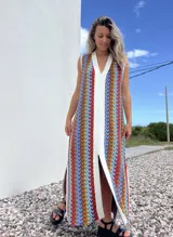 Vestido largo de tejido con diseño geométrico en tonos celeste, marrón, rojo y blanco. Tiene escote en V y aberturas laterales.