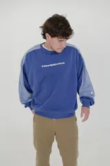Buzo azul con mangas raglán en tono celeste y puños ajustados. Estampa frontal con la palabra "CONFIDENTIAL" en mayúsculas.