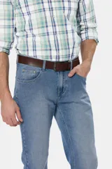 Pantalón de jean azul oscuro de corte recto y tiro medio. Incluye cinturón de cuero marrón y botas de gamuza marrón.