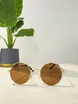 Lentes de sol con montura metálica dorada y cristales color marrón.
