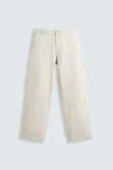 Pantalón color beige, de corte relaxed fit, con cinco bolsillos, efecto lavado, aplicación de tira y bolsillo multifunción en perneras. Cierre frontal con cremallera y botón.