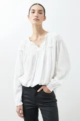Blusa blanca de estilo boho con escote con volados y lazos, mangas largas abullonadas con puños elásticos.