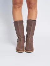 Bota de caña media color marrón, confeccionada en cuero. Presenta una correa con hebilla metálica alrededor del tobillo y un taco de madera.