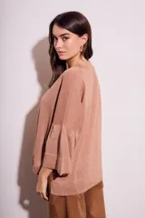 Sweater color salmón de tejido de punto con lurex, corte oversize, cuello redondo y mangas 3/4 acampanadas.