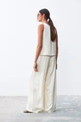 Pantalón palazzo color crudo, de tiro alto y corte holgado.