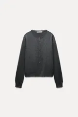 Chaqueta de punto fino color gris oscuro confeccionada con lana. Tiene cuello redondo, manga larga y cierre frontal con botones.