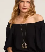 Blusa blanca de viscosa con escote off-shoulder y mangas 3/4 abullonadas con lazos en los puños.