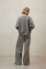 Buzo de tejido liso color gris, con cuello redondo y puños y ruedo ajustados.