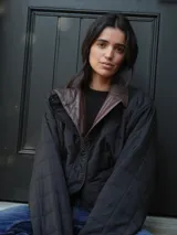 Campera puffer azul marino con diseño acolchado de rombos, cuello de cuero sintético negro, mangas largas abullonadas con puños elásticos y cierre frontal con cremallera.