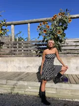 Vestido corto strapless de modal con estampado de lunares blancos sobre fondo negro, detalle de puntilla en el busto, fruncido en los laterales y falda con vuelo.