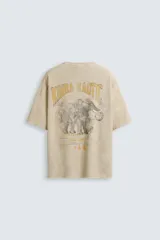 Camiseta color beige de punto tejido en hilatura de algodón, corte relaxed fit, cuello redondo y manga corta. Estampación con efecto lavado combinada a contraste en espalda. Acabados irregulares.