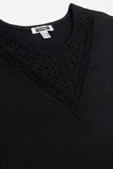 Remera blanca de algodón con cuello redondo y mangas cortas. Presenta detalle de broderie en forma de V en el escote.