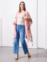 Kimono tejido con estampado abstracto en tonos beige, blanco y negro. Tiene mangas amplias estilo japonés y terminación de ruedo con borlas.