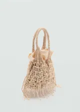 Bolso pequeño color beige, con diseño de red de macramé con flecos. Tiene asa corta trenzada y asa larga de cadena extraíble. Incluye bolsa interior de tela.