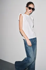 Pantalón de jean azul de tiro bajo, corte wide leg y largo hasta el tobillo. Tiene cinco bolsillos, trabillas en la cintura y cierre frontal con cremallera y botón metálico.