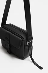 Bandolera negra de acabado engomado, con compartimento principal con cierre de cremallera y bolsillo interior con cremallera. Bolsillo frontal con cierre de hebilla de liberación rápida. Asa de hombro ajustable y extraíble.