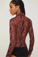 Body de poliéster y elastano con estampado de piel de serpiente en tonos marrones y negros. Tiene mangas largas, escote en V cruzado y calce ajustado al cuerpo.