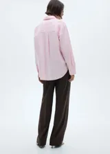 Camisa rosada de algodón con corte recto, cuello camisero, manga larga con puños abotonados, bolsillo de parche en el pecho y cierre frontal con botones.