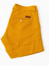 Short de lino color mostaza con bolsillos traseros con botón y etiqueta de cuero con logo de la marca.