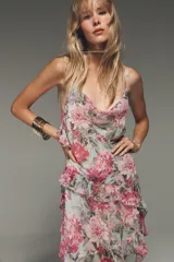 Vestido corto con estampado floral en tonos rosa y verde, escote fluido, tirantes finos y volantes en el lateral.
