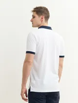 Remera polo blanca de piqué con cuello y puños en azul marino. Tiene tapeta de dos botones y bolsillo de parche en el pecho.