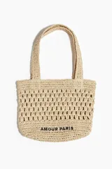 Bolso tote color beige, tejido en paja de papel trenzada, con doble asa corta y texto 'Amour Paris' en negro.