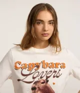Remera blanca de algodón con cuello redondo y mangas cortas. Estampa frontal con la frase "Capybara Lovers" y un dibujo de un carpincho.