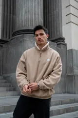 Buzo beige de pana con cuello alto forrado en corderito blanco, cierre parcial con cremallera, puños y cintura elastizados.