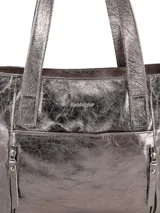 Bolso tipo shopper de mujer, color peltre (gris metálico con acabado arrugado/crush). Presenta dos asas de hombro y múltiples cierres externos con cremallera.