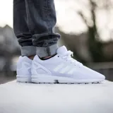 Zapatillas Adidas ZX Flux blancas con las tres tiras laterales características de la marca.