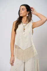 Blusa beige de lino bordado, sin mangas y con terminación en flecos.
