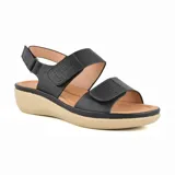 Sandalias bajas negras con plataforma color beige, tiras anchas con perforaciones y ajuste con hebilla.