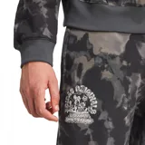 Pantalón largo de jogging Adidas Originals para hombre, con estampado tie-dye en tonos grises y negros, cintura elástica ajustable con cordón, bolsillos laterales y logo "Adidas Originals Mellow Sports Club" estampado en blanco en la pierna izquierda.