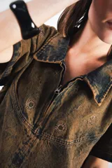 Vestido corto de denim celeste con cuello tipo camisa, cierre frontal metálico y bolsillos delanteros. Presenta bordados de soles y lunas en el canesú delantero y trasero.