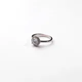 Anillo de plata 925 con circonias engarzadas. El anillo tiene un diseño delicado y elegante, con una circonia central redonda rodeada de pequeñas circonias brillantes.