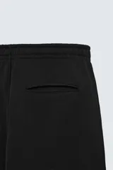 Pantalón jogger gris de corte recto, confeccionado en tejido de algodón compacto con interior en rizo. Tiene cintura elástica ajustable con cordón interior, bolsillos frontales y bolsillo de doble vivo en la espalda.