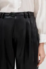 Pantalón negro de poliéster recubierto con poliuretano, corte cropped y tiro alto.