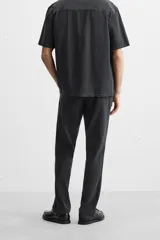 Pantalón negro de corte recto, confeccionado en tejido de mezcla de algodón y lino. Presenta cintura elástica, bolsillos laterales y traseros.