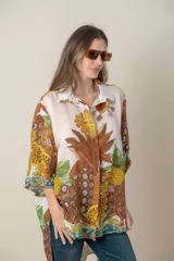 Camisa italiana de viscosa estampada con diseño abstracto en tonos azul, amarillo y verde sobre fondo natural, de corte irregular y mangas 3/4.