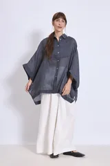 Camisa blanca de lino con cuello clásico, cierre frontal con botones, mangas anchas 3/4 y detalles de bordado calado en el canesú y los puños.