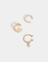 Set de tres aros dorados para la oreja, tipo cuff, con diferentes diseños: uno liso con calados de corazón, uno con eslabones y uno con strass colgante.