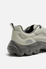 Zapatillas grises con cordones, capellada combinada y suela chunky con diseño irregular.