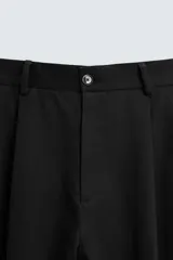 Pantalón negro de corte ancho, con pinzas en la cintura, bolsillos laterales y traseros de ojal.