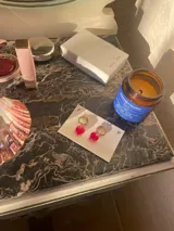 Aros colgantes con argolla dorada de acero inoxidable y dije de vidrio rojo en forma de corazón.