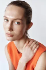 Top tejido de punto color naranja, de cuello redondo y sin mangas. Tiene corte ajustado en el torso y peplum en la cintura.
